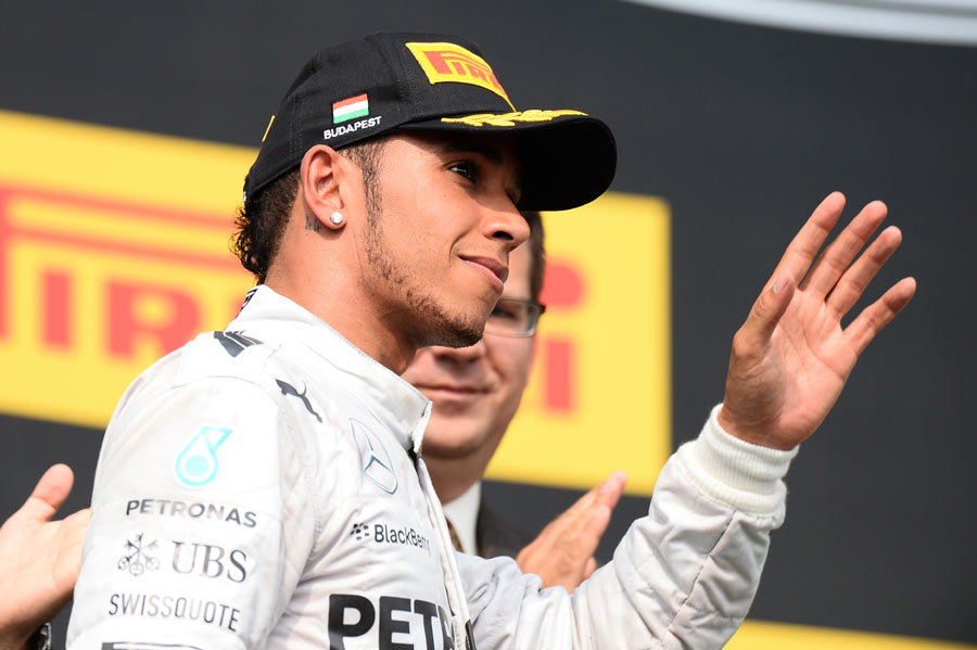 Lewis Hamilton waves to the crowd as he walks out to the podium