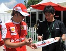 Fernando Alonso signs an autograph for a fan