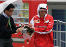 Kimi Raikkonen signs an autograph as he arrives in the wet Suzuka paddock
