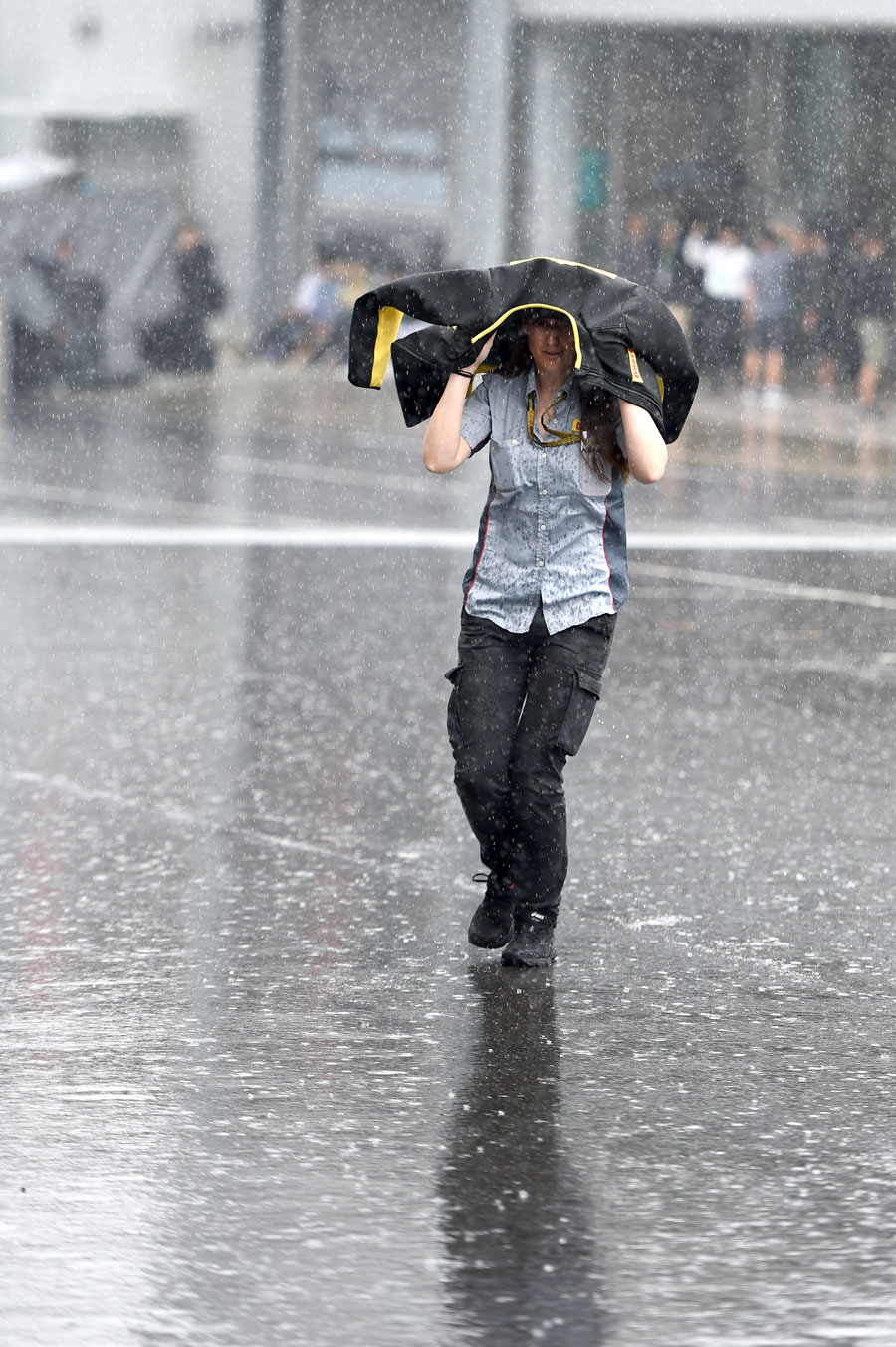 A Pirelli employee arrives at the paddock sheltering from the heavy rain