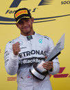 Lewis Hamilton celebrates with the winners' trophy on the podium