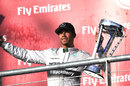 Lewis Hamilton celebrates with the winner's trophy on the podium