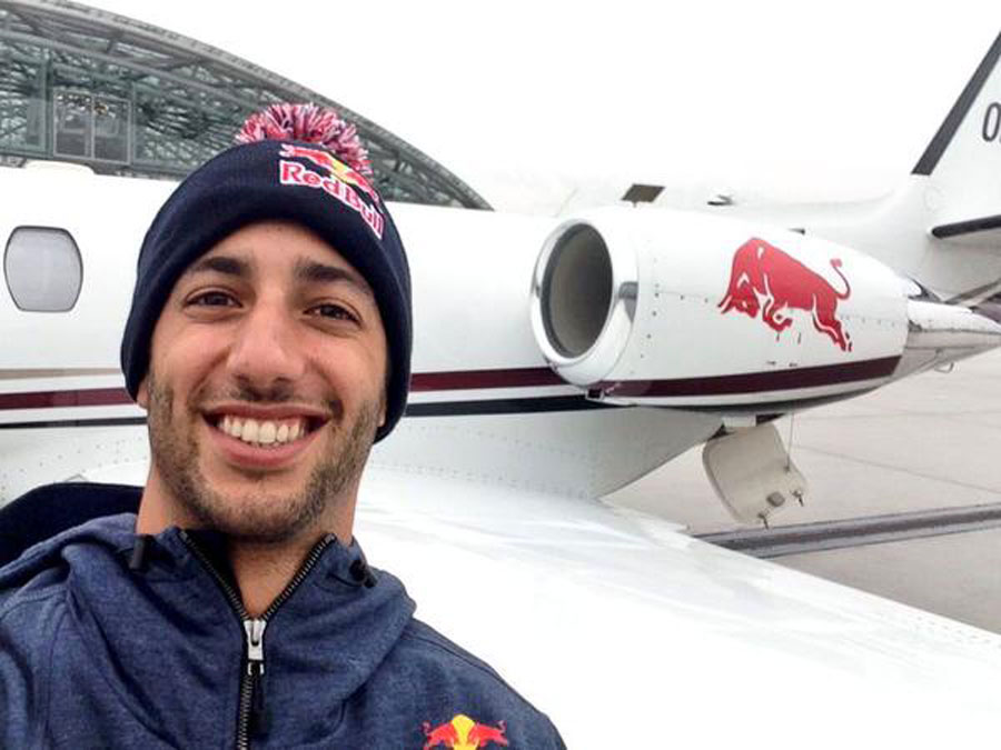 Daniel Ricciardo poses for a selfie in front of a Red Bull jet