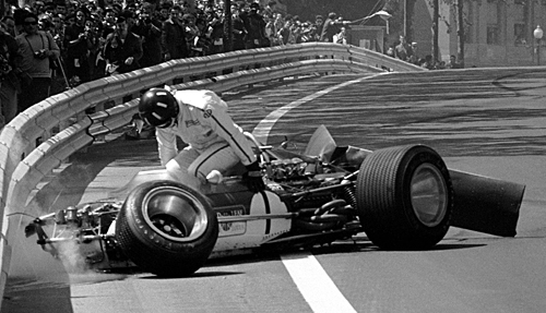 Graham Hill climbs from the wreckage of his Lotus