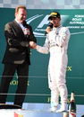 Lewis Hamilton shakes hands with film star Arnold Schwarzenegger on the podium