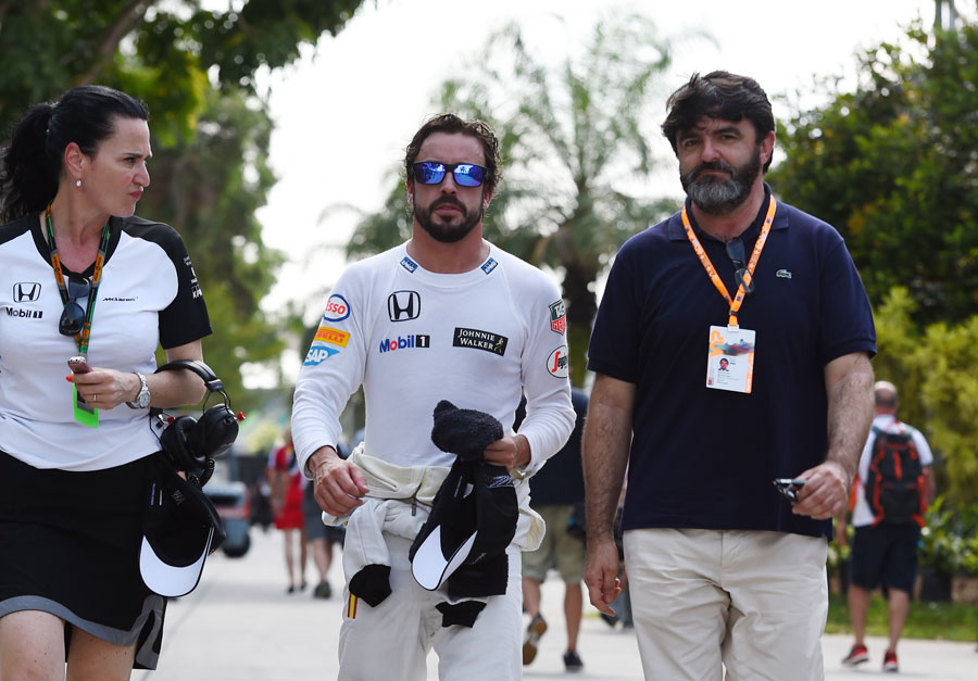 Fernando Alonso walks through the paddock after retiring from his first race with McLaren-Honda
