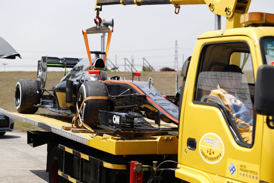 Fernando Alonso's McLaren MP4-30 is recovered after stopping on track