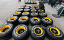 A Lotus mechanic paints the initials of Jarno Trulli on his tyres 