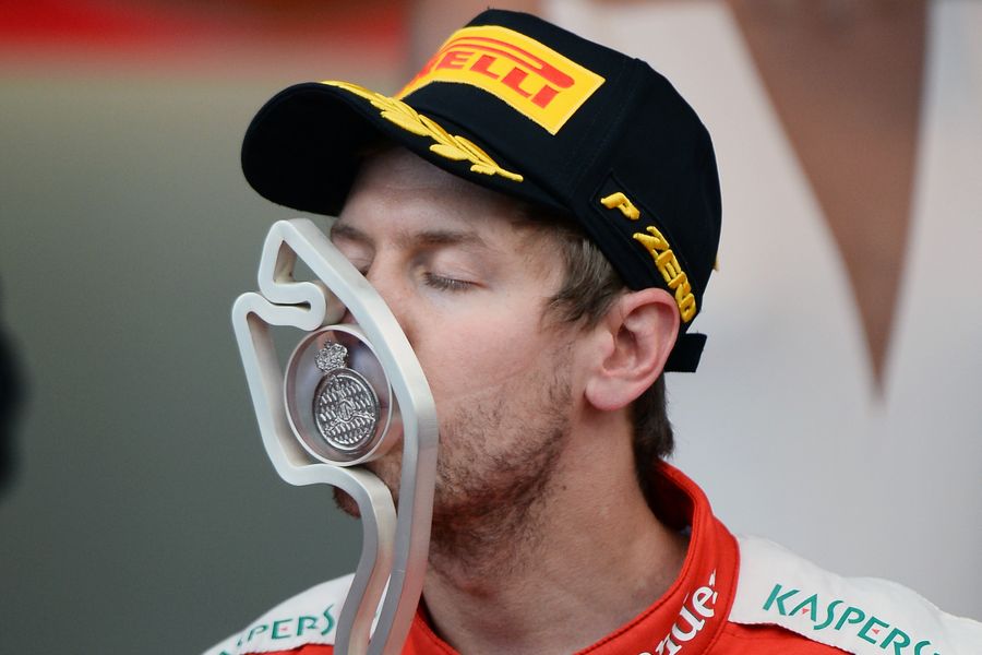 Sebastian Vettel celebrates by kissing the trophy on the podium