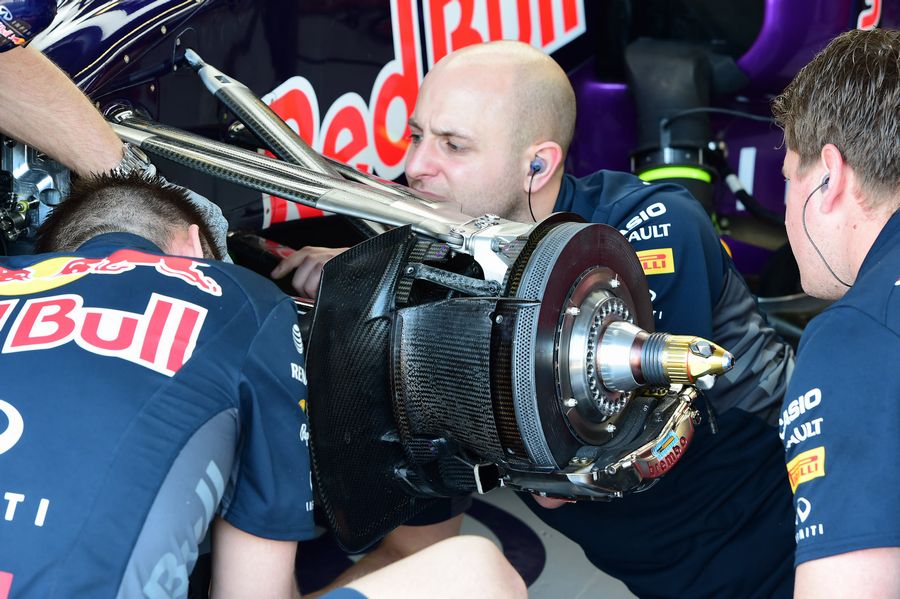 Red Bull mechanics work on front brake and wheel hub of the RB11