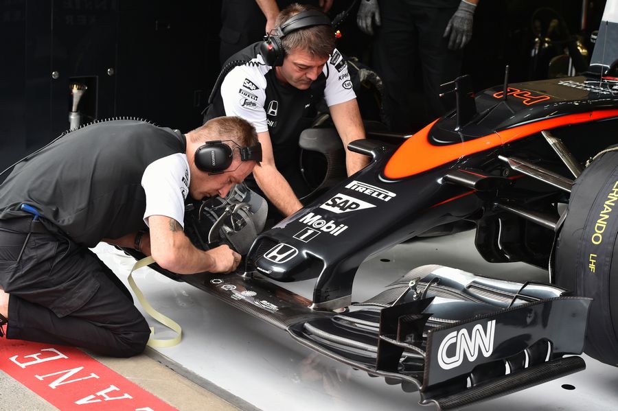 McLaren mechanics work with the McLaren MP4-30 nose and front wing
