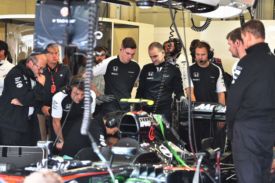 McLaren mechanics work on Jenson Button's MP4-30 in the garage