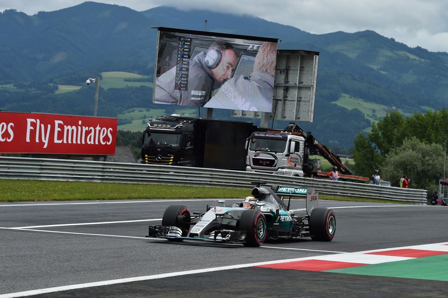 Lewis Hamilton passes screen showing Paddy Lowe