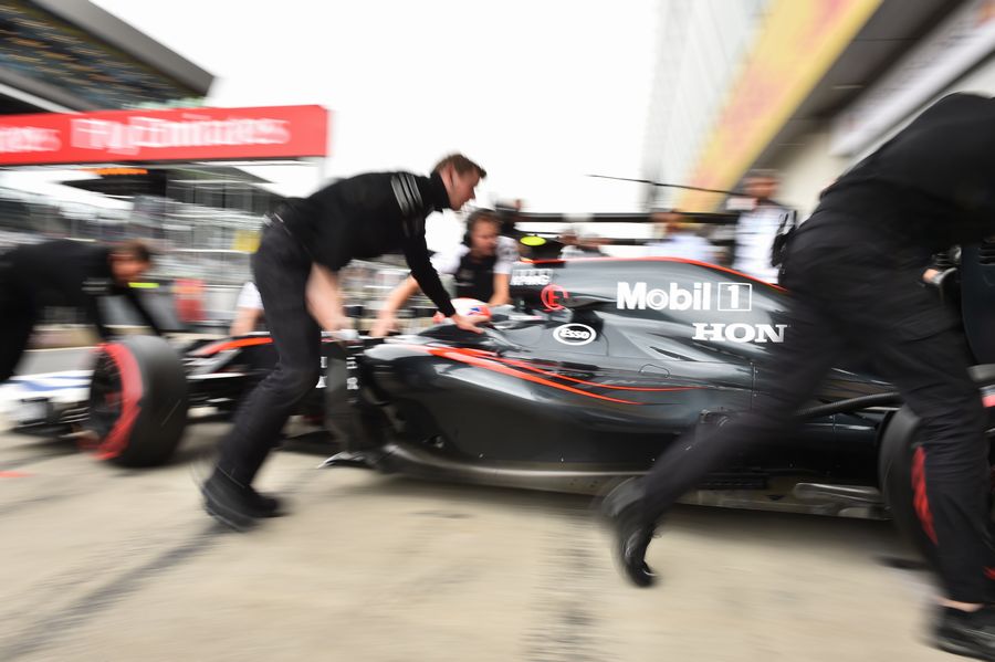 McLaren mechanics wheel Jenson Button back into the garage