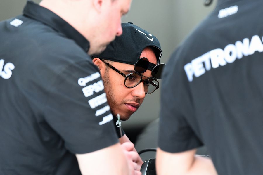Lewis Hamilton works with engineers in the Mercedes garage