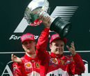 Michael Schumacher encourages Rubens Barrichello to take the winner's trophy