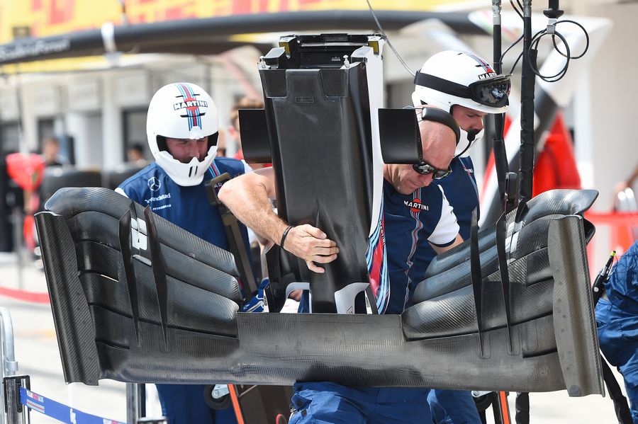 Williams mechanics carry a front wing of FW37 through the paddock