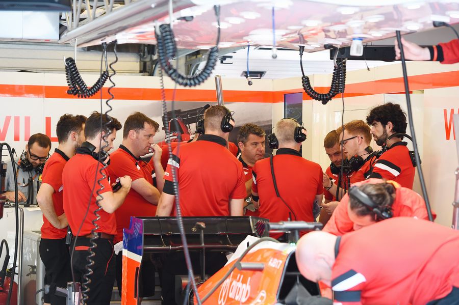 Manor Marussia mechanics wearing a black armband in respect of the late Jules Bianchi