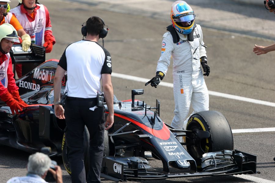 Fernando Alonso gives over his MP4-30 to McLaren mechanics after engine failure in Q2