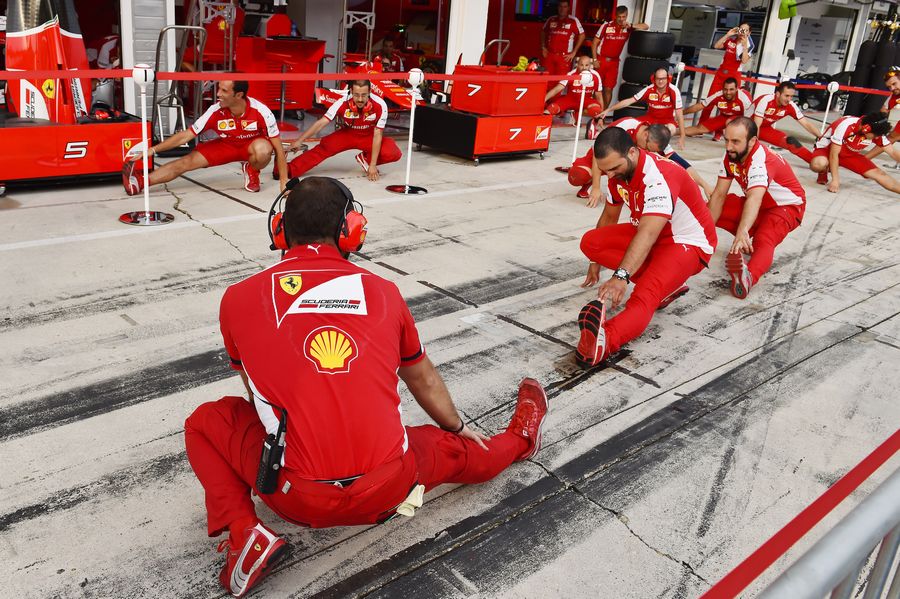 Ferrari mechanics performing warm-up exercises before pitstop practice