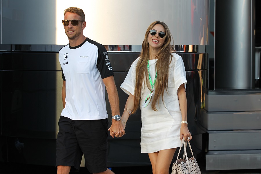 Jenson Button walks through the paddock with his wife Jessica