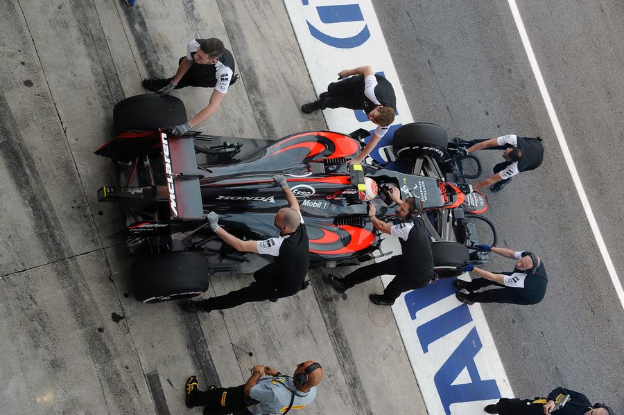 Jenson Button's MP4-30 is wheeled back into the McLaren garage