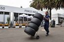 A Sauber mechanic wheels some Pirelli tyres through the paddock 