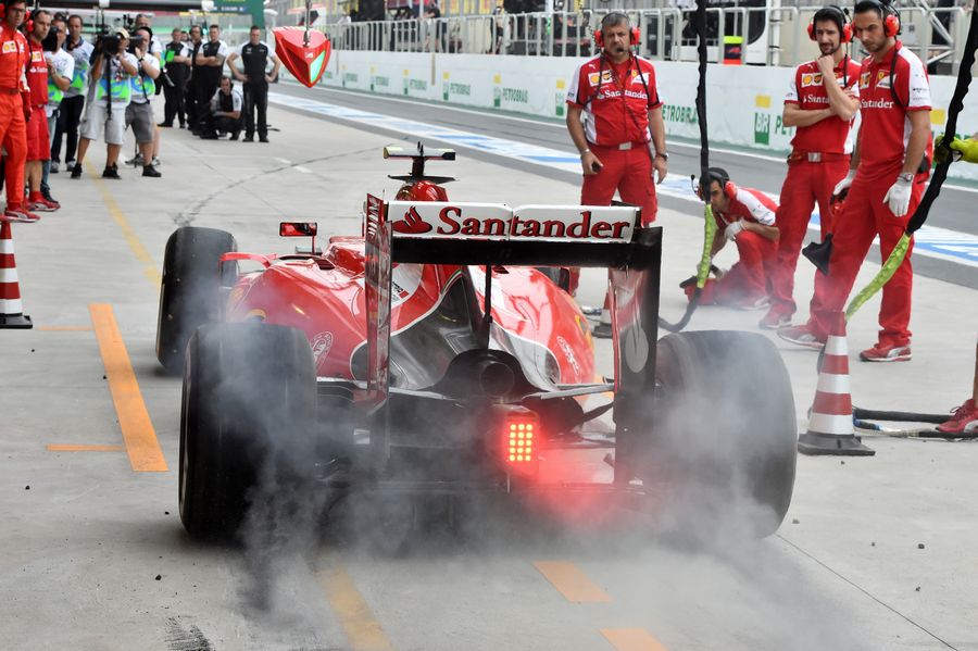 Kimi Raikkonen's Ferrari emits some smoke as he returns to the pit