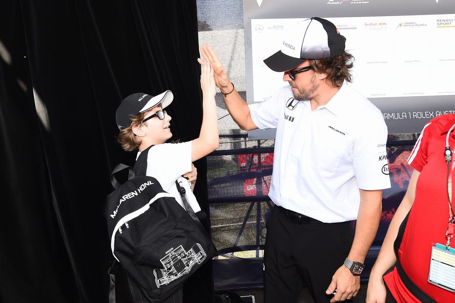 Fernando Alonso high fives with a young fan