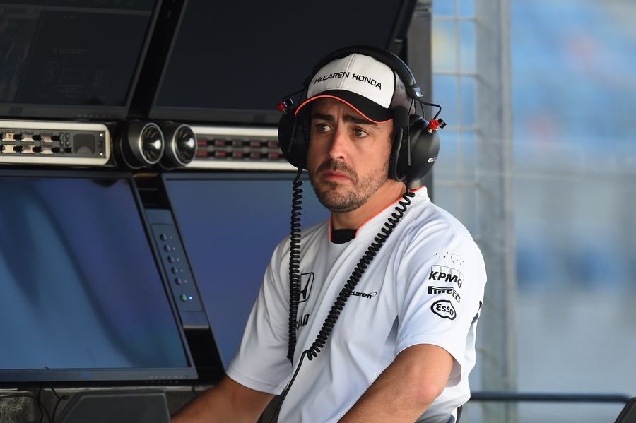 Fernando Alonso watches on from the team pit wall