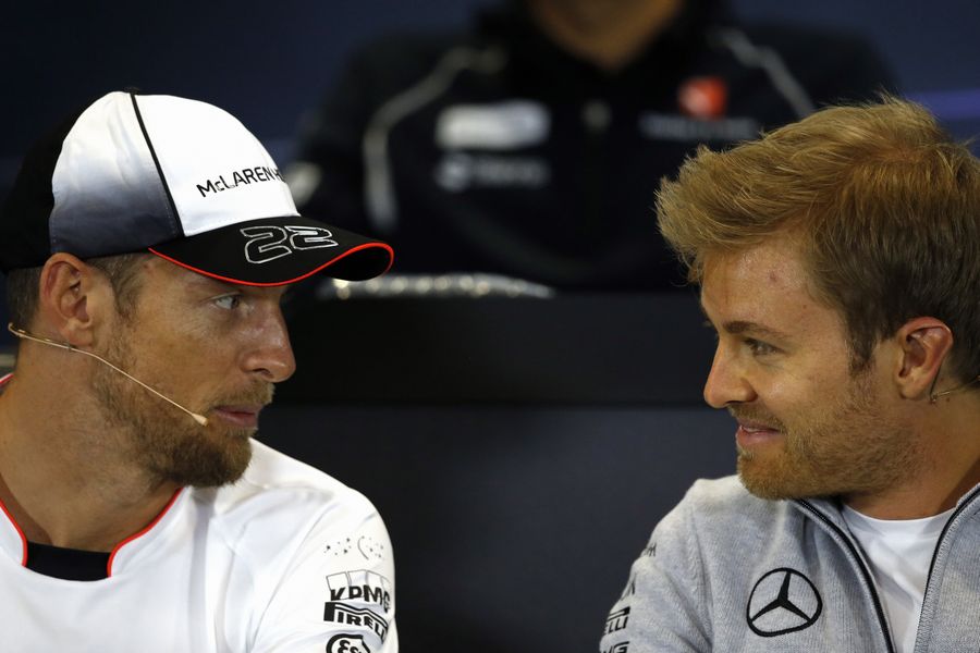 Jenson Button speaks with Nico Rosberg during the press conference
