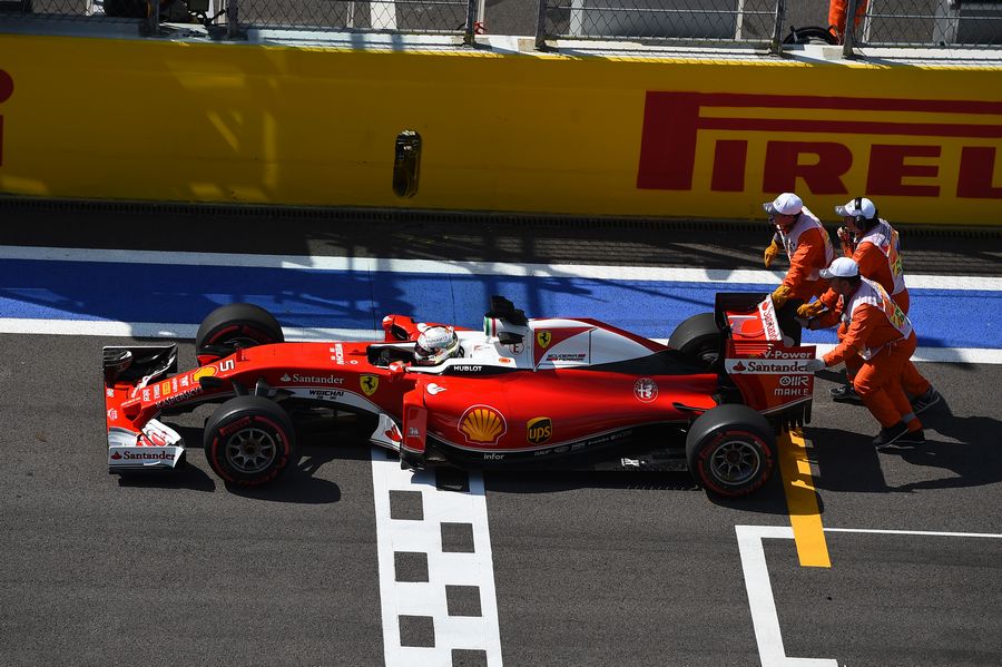 Sebastian Vettel in the Ferrari is pushed by the marshals in FP2