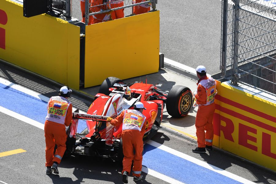 Sebastian Vettel in the Ferrari is pushed into pit lane by the marshals in FP2