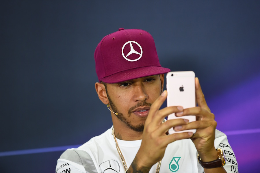 Lewis Hamilton takes a picture on his mobile during the press conference