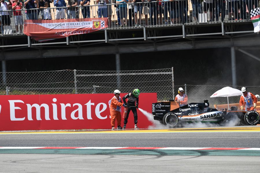 Nico Hulkenberg battles the fires after grabbing the fire extinguisher off the marshal