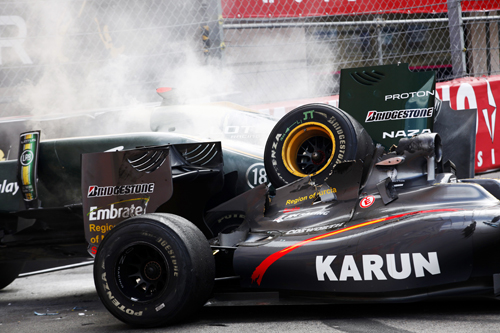 Smoke comes off the crashed cars of Jarno Trulli's Lotus and Karun Chandhok's HRT