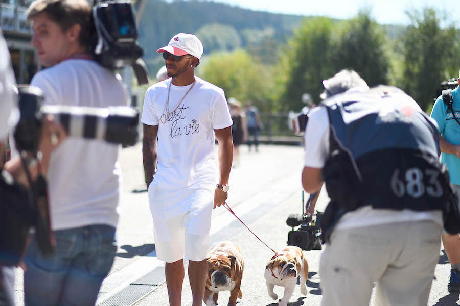 Lewis Hamilton walks through the paddock with his dogs