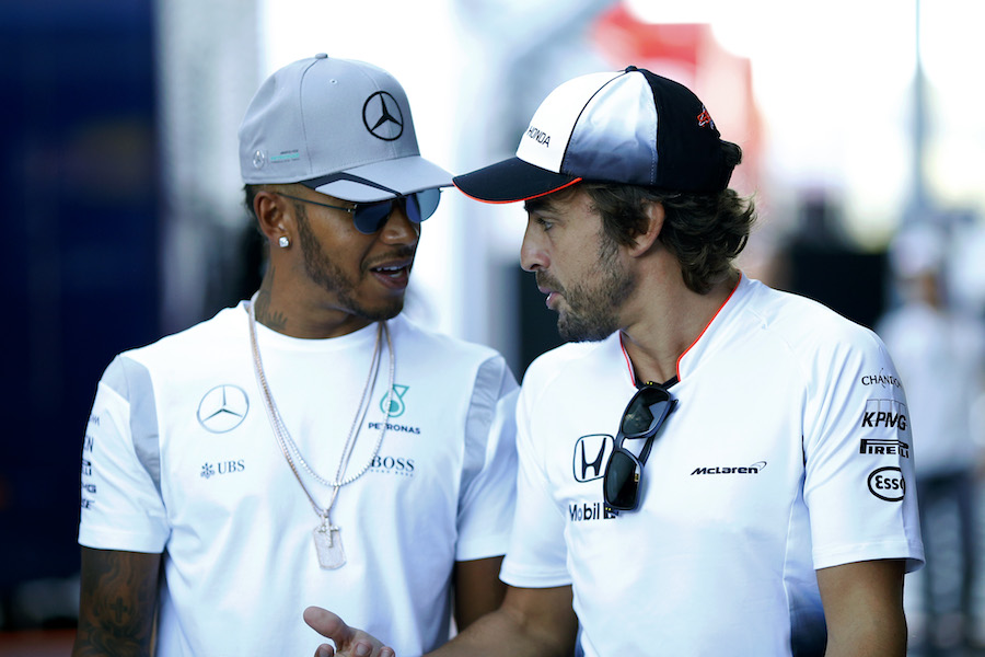 Lewis Hamilton and Fernando Alonso walk through the paddock
