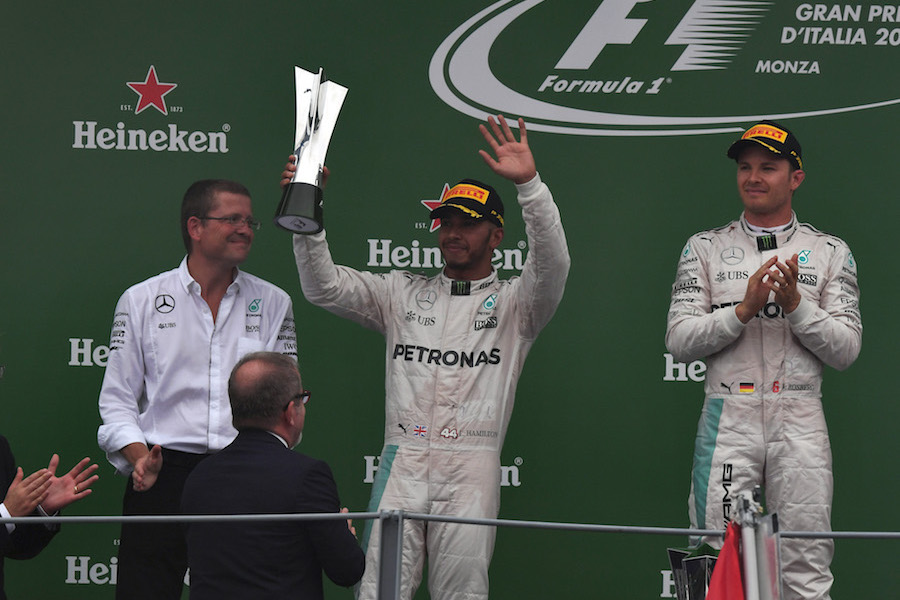 Lewis Hamilton celebrates on the podium with the trophy 