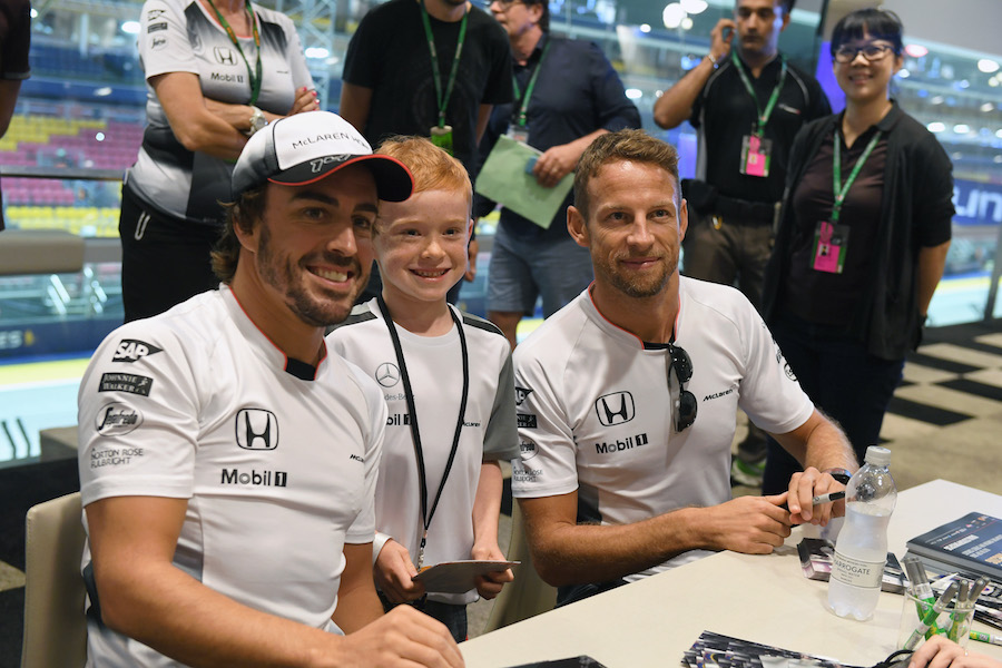 Fernando Alonso and Jenson Button take a picture with a young fan