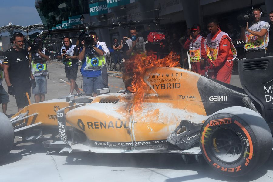 The burning car of Kevin Magnussen in pit lane