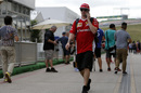 Kimi Raikkonen walks through the paddock using the phone