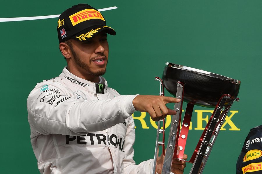 Lewis Hamilton celebrates on the podium with the trophy
