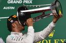 Lewis Hamilton celebrates on the podium with the trophy and champagne