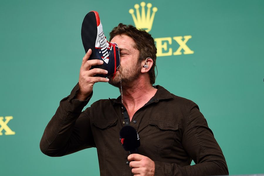 Gerard Butler drinks from the boot of Daniel Ricciardo on the podium