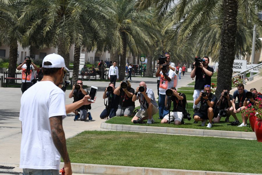 Lewis Hamilton takes a picure for photographers