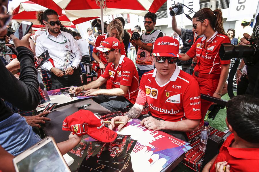 Kimi Raikkonen and Sebastian Vettel sign for a fan