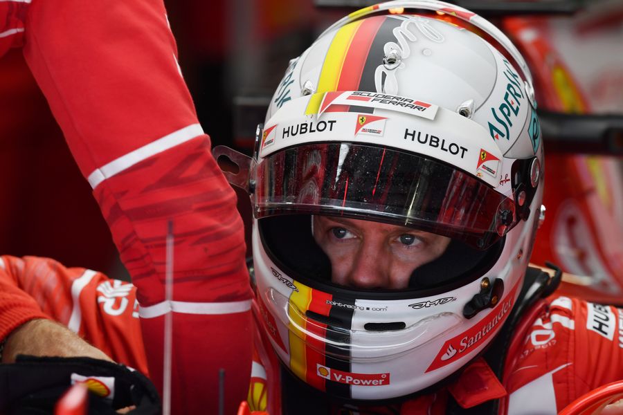 Sebastian Vettel sits in the Ferrari cockpit in the garage