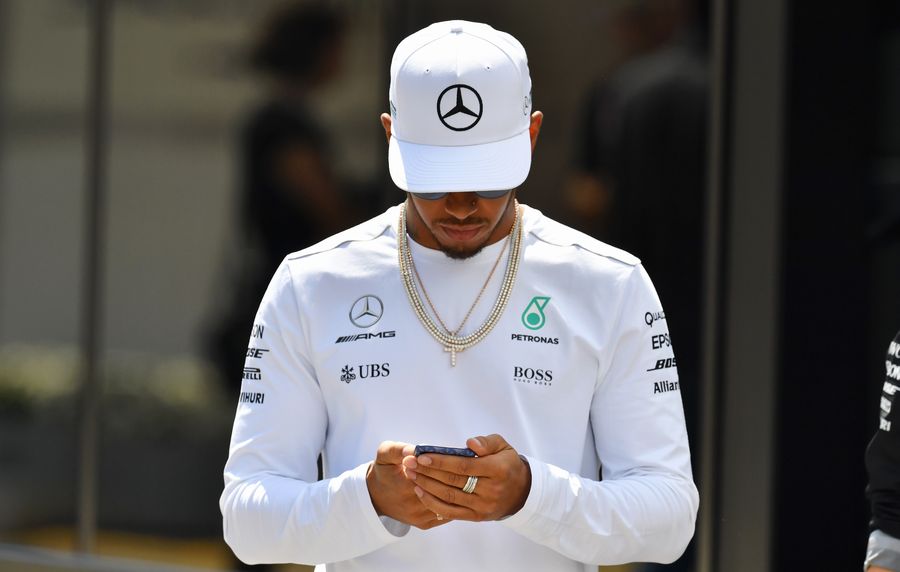 Lewis Hamilton checks his phone in the paddock