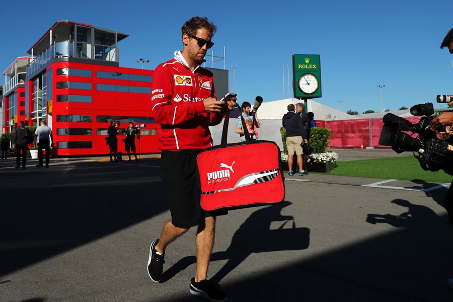 Sebastian Vettel checks his phone in the paddock